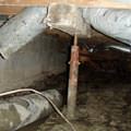Rusty steel crawl space jack post supports in a structure in Greer.