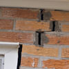 A brick wall displaying stair-step cracks and messy tuckpointing on a Augusta home