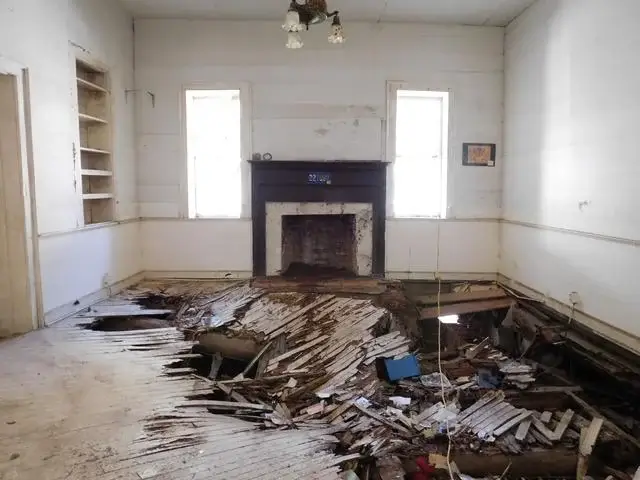 All the clutter and debris collapsed the rotten wood floor in both rooms.