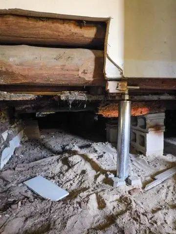 This picture illustrates the old wooden stumps that were used as central beams in this 150 year old house. The production crew placed a SmartJack temporarily as to hold the structure up while working on one room at a time.