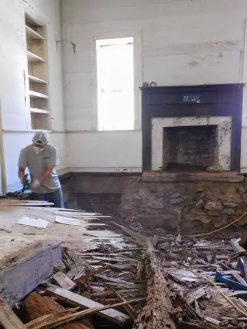 Production crew member Ryan removes the rotted floors.