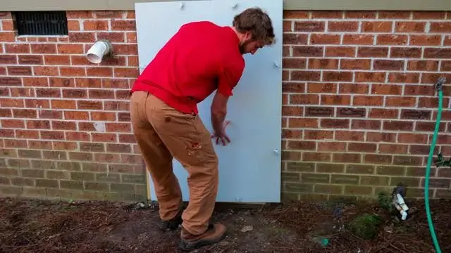 After showing the CleanSpace system to Donald, Production Team Member Jonathan fastens the crawl space door tightly.